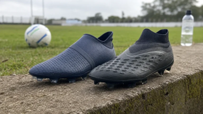 Duas chuteiras de campo sem marca num degrau à beira do campo, uma de malha com pontos impressos e outra com relevos no bico